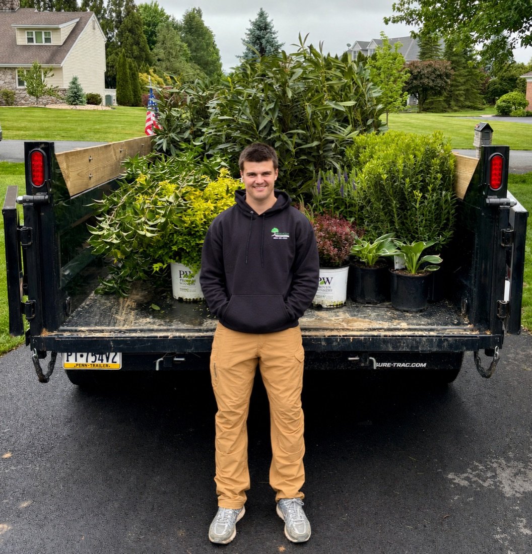 Reilly, owner of Bechtel's Landscaping, standing in front of a trailer loaded with plants for an installation